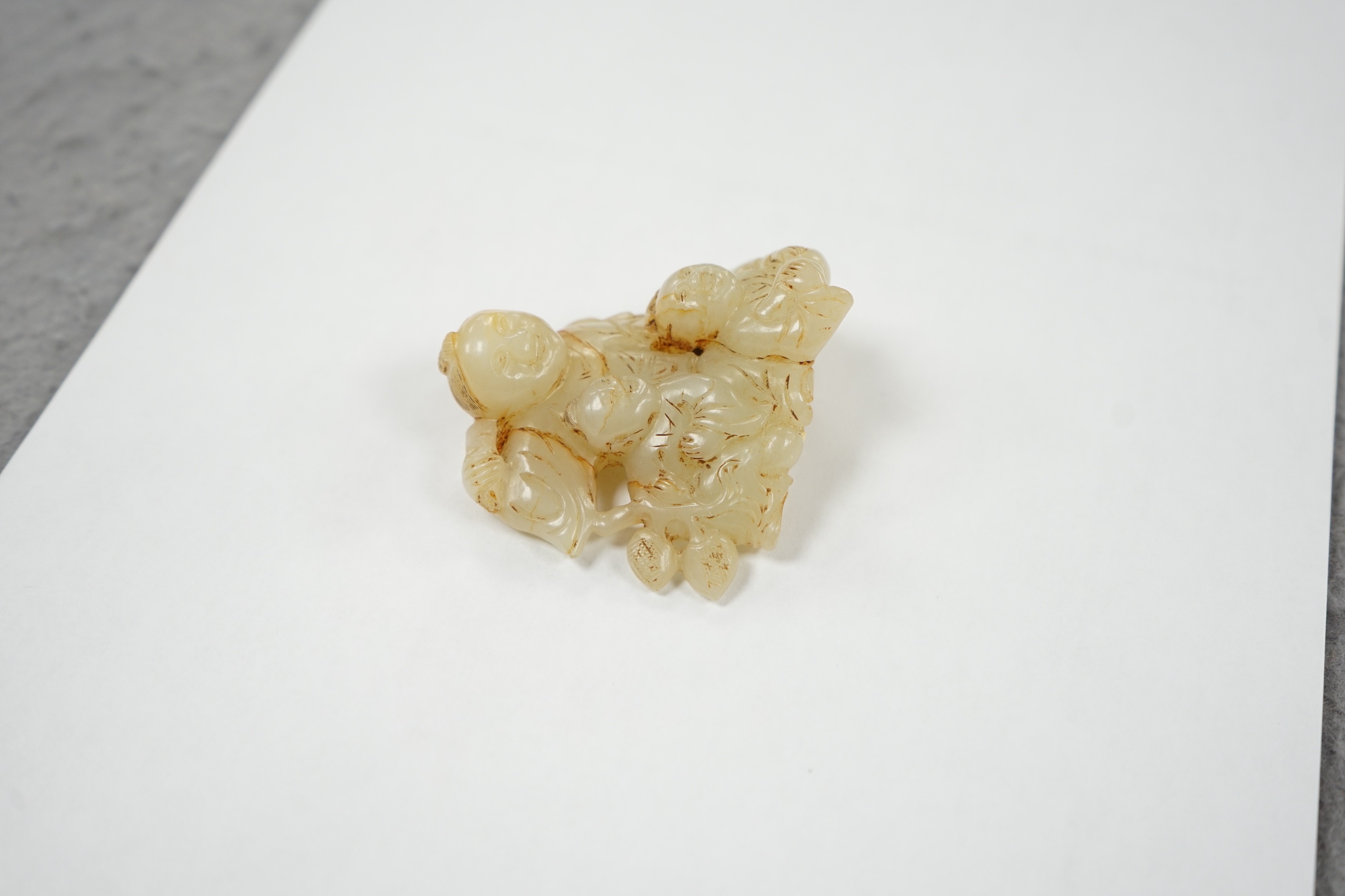 A Chinese white and russet jade group of three boys, 18th/19th century, 7.2 cm, wood stand